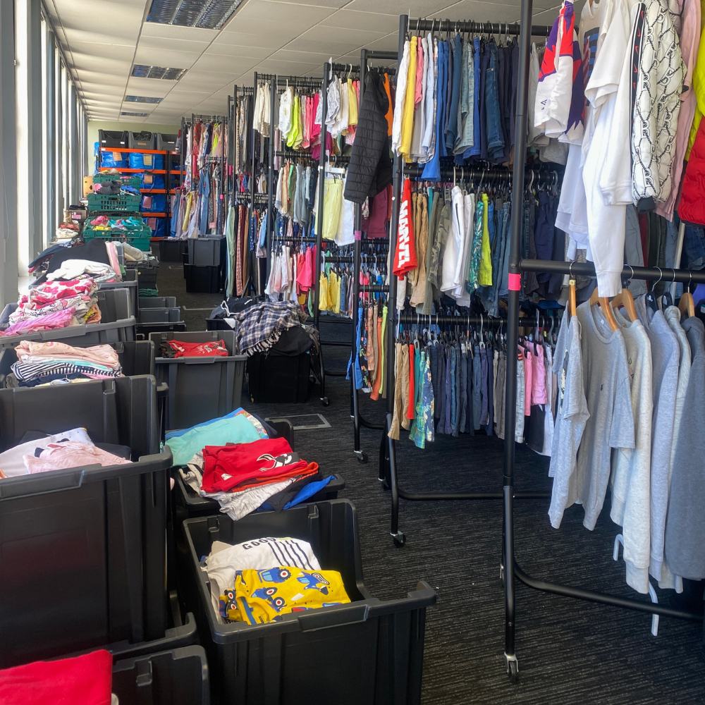 Clothing store with racks and bins filled with various garments.