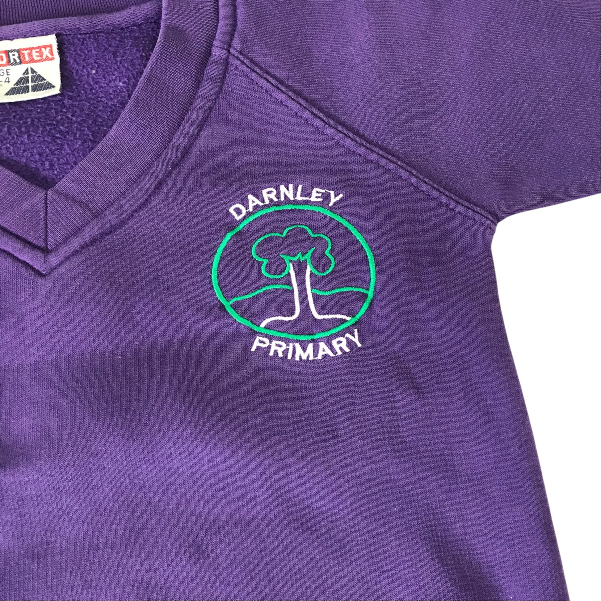 Second-hand Darnley Primary boys purple V-neck jersey sweatshirt, flat lay view with embroidered school badge.